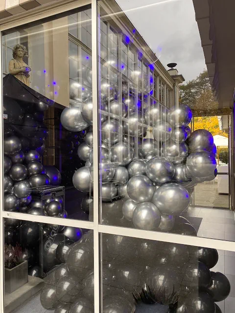 Balonowa aranżacja w czarnych, srebrnych i fioletowych kolorach, ustawiona w stylowej sali Belvedere z widokiem na ogród. Oświetlenie tworzy magiczną i wyrafinowaną atmosferę