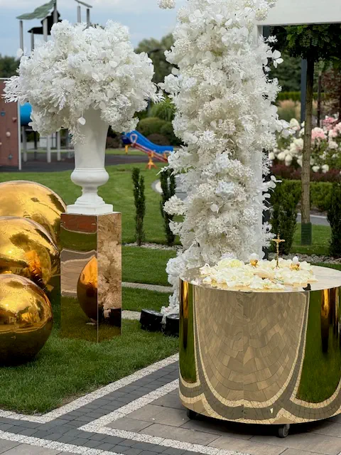 Elegancka dekoracja w ogrodzie Hotelu Rubin koło Radomia z białymi kwiatami, złotymi kulami i lśniącym stołem