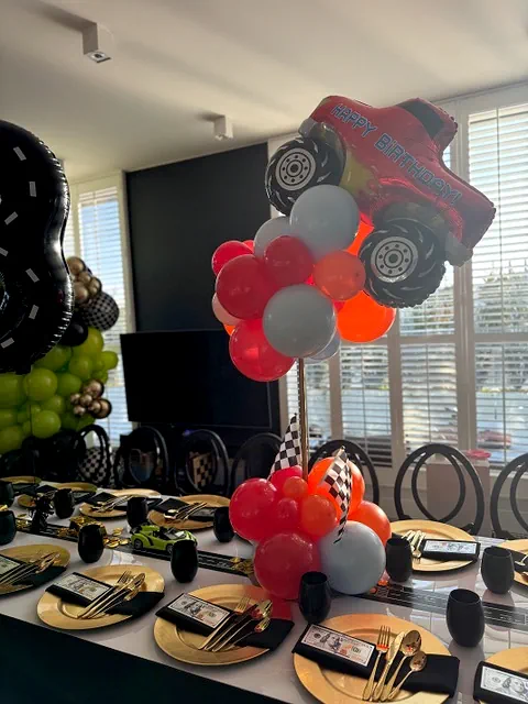Elegancka dekoracja urodzinowa w Warszawie z motywem wyścigowym, złote talerze, czarne serwetki, balony w kształcie samochodu i toru wyścigowego